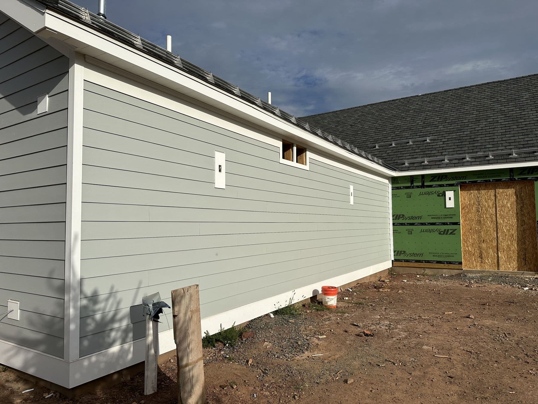 Long side wall of the house in gray lap siding with white corners