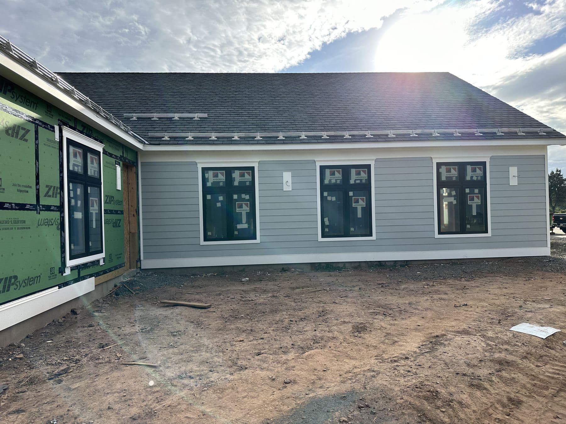 Rear wall in gray lap siding next to an unsided section of green sheathing
