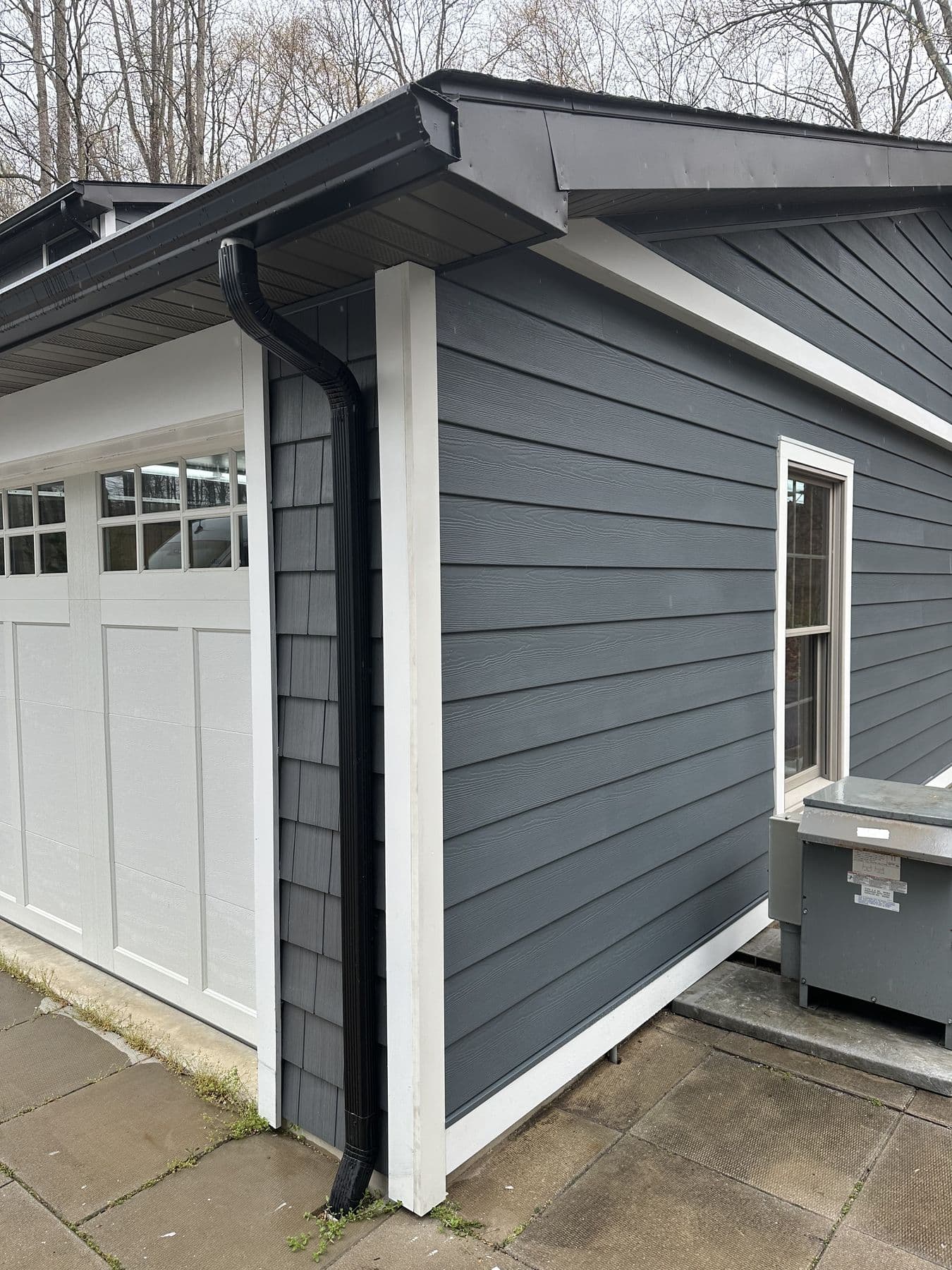 Garage side of the house in blue-gray lap siding with a black gutter and downspout