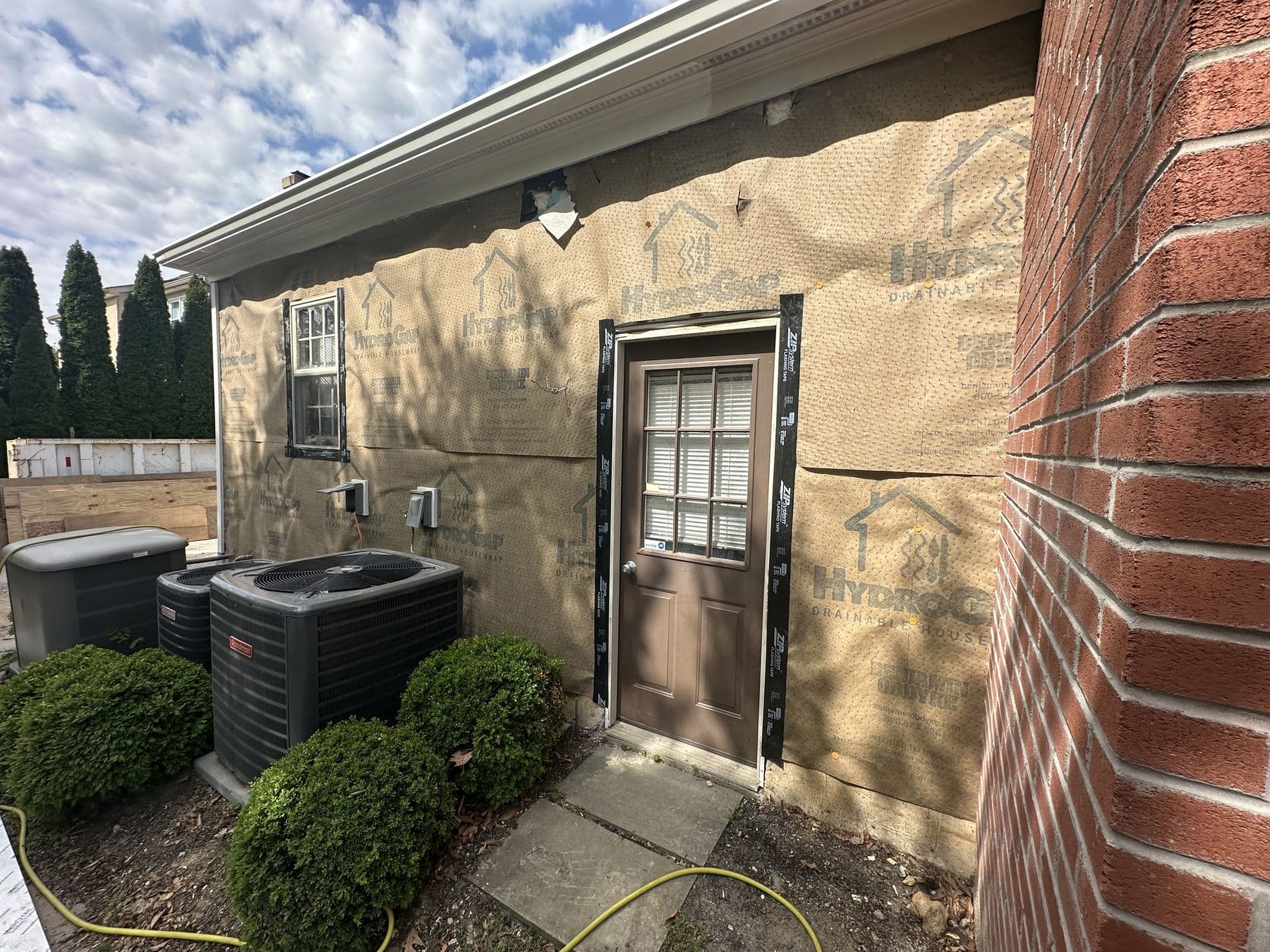 Wall stripped to sheathing around a door and the AC units