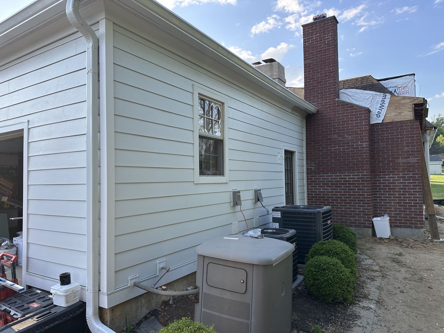 Finished white siding with new window trim beside the brick chimney