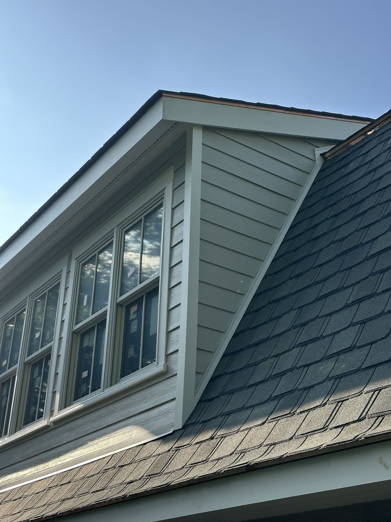 Dormer cheek wall in gray lap siding against the slate-style shingle roof