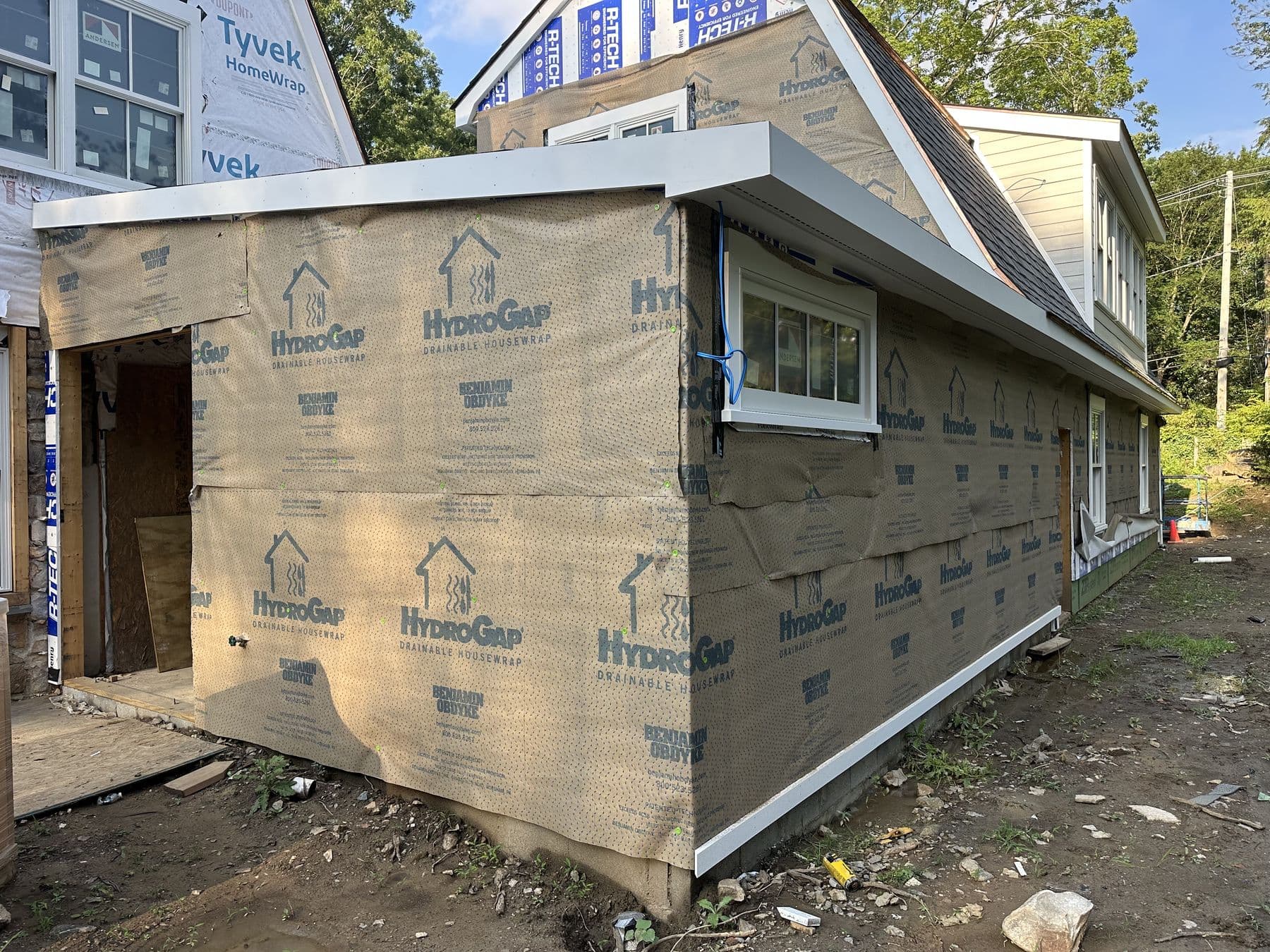 Addition wall wrapped in housewrap with window openings before siding