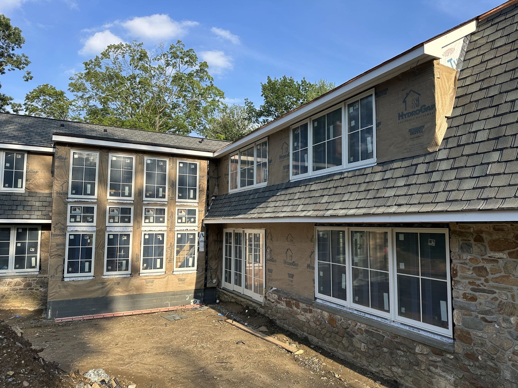 Corner of the house where the stone wing meets the new addition with a wall of new windows
