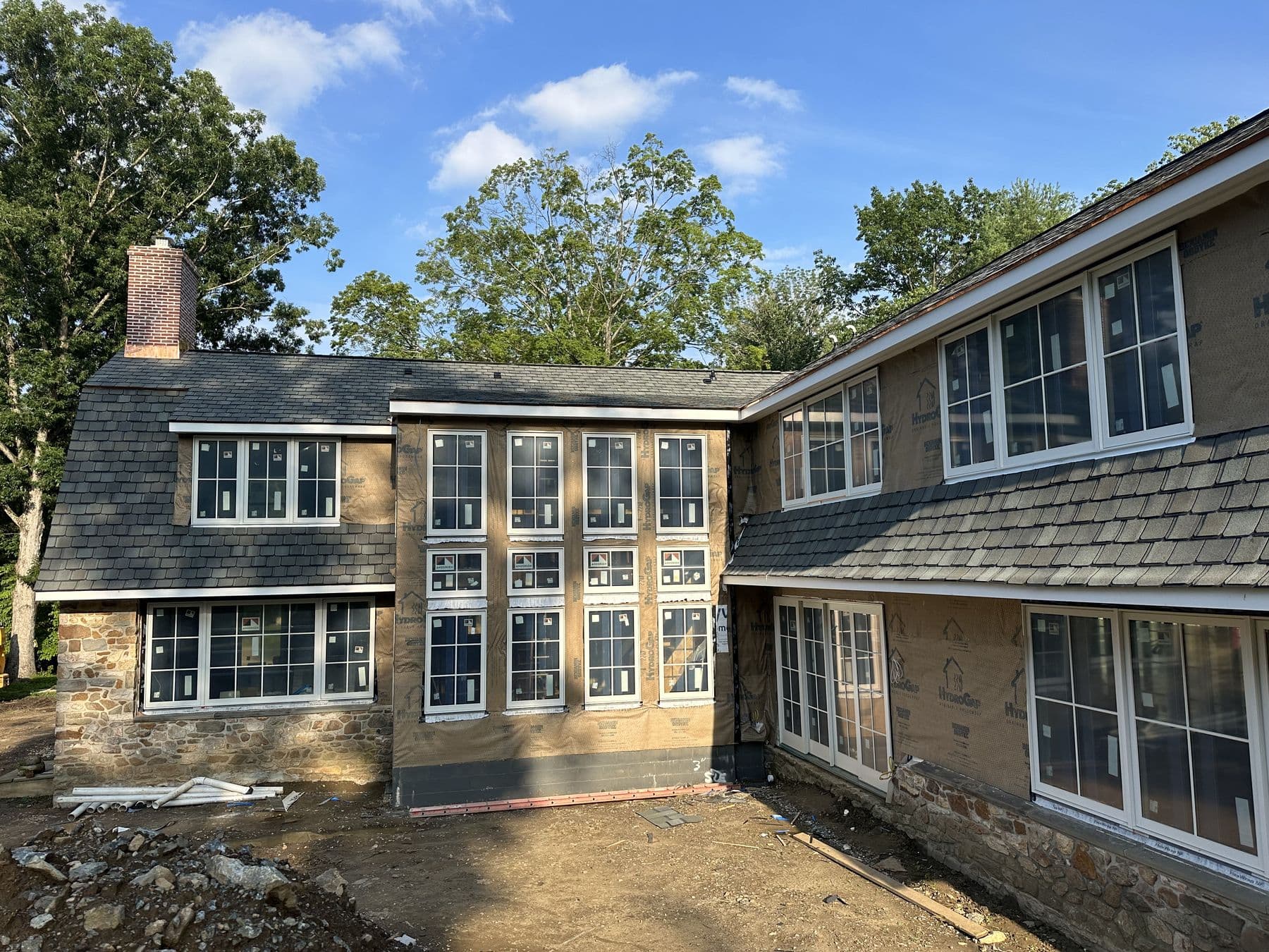 Stone wing and new addition side by side, the addition still in housewrap