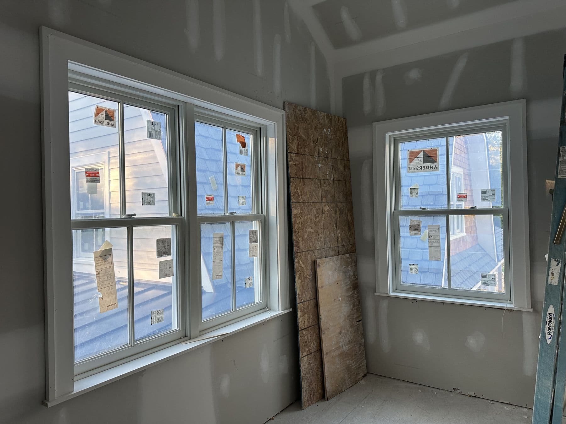 Corner of a new room with two banks of windows and a stone wall section