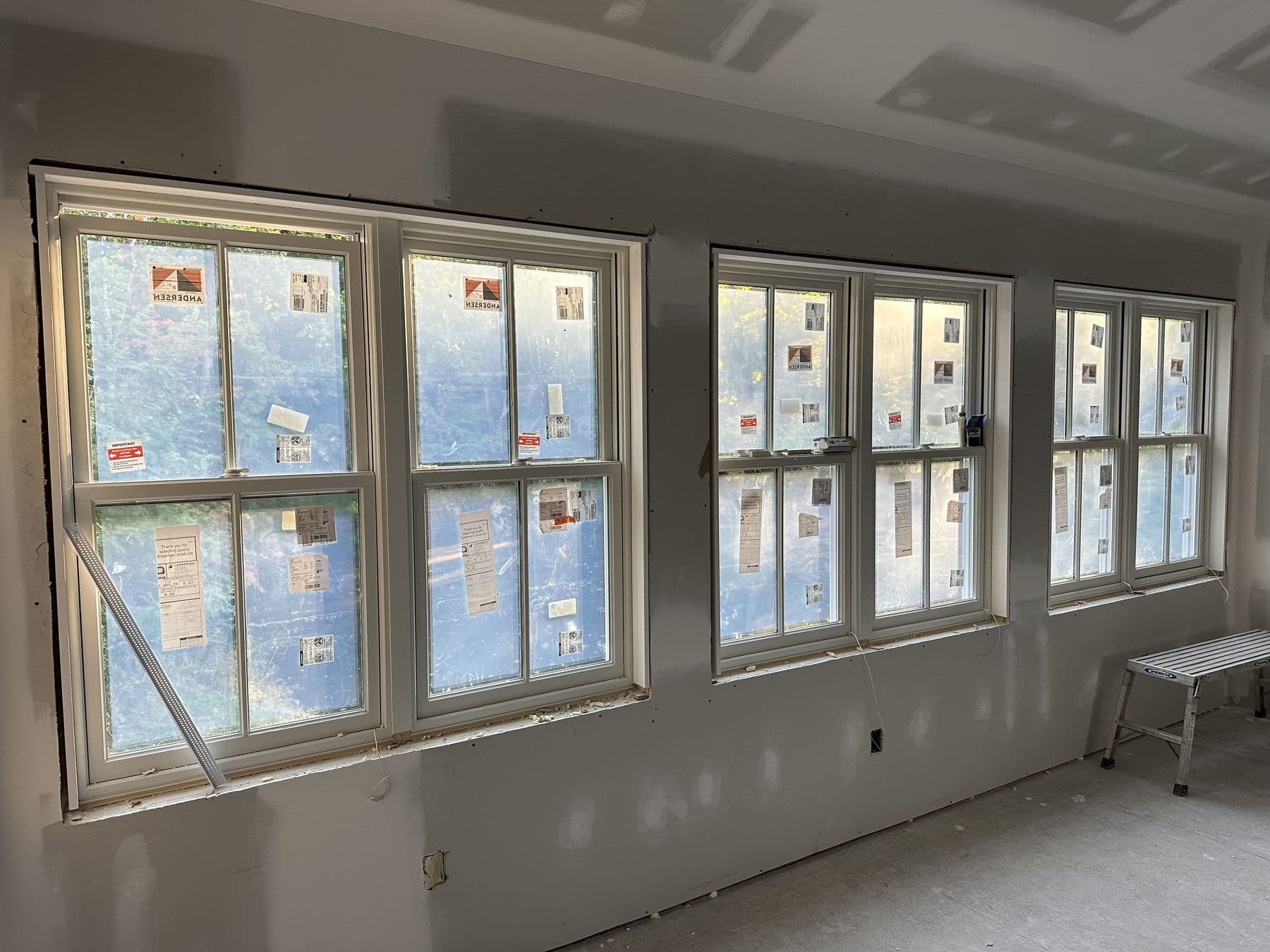 Wide view of new windows in a gambrel addition room with drywall finished