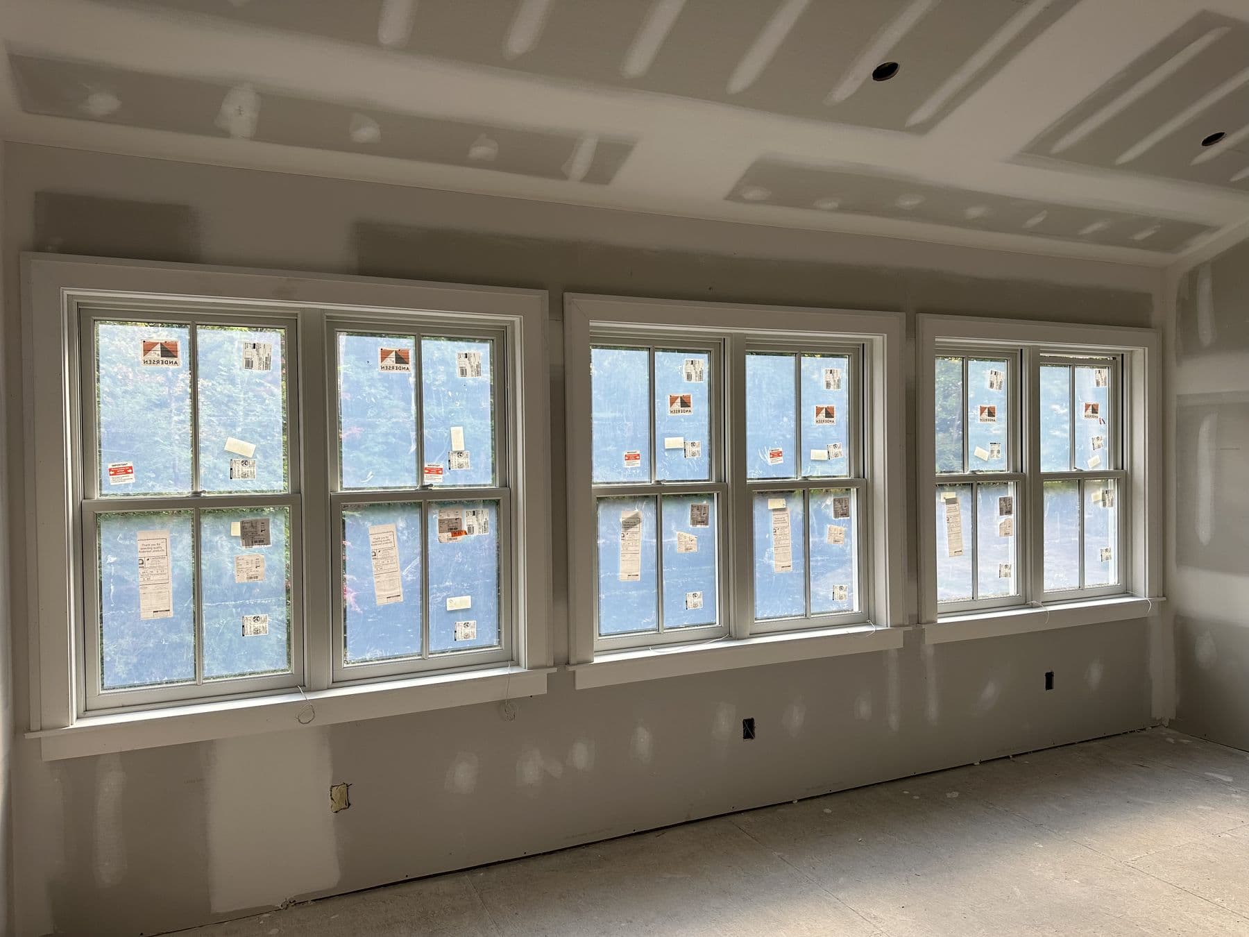 Three window units trimmed in white across a long wall