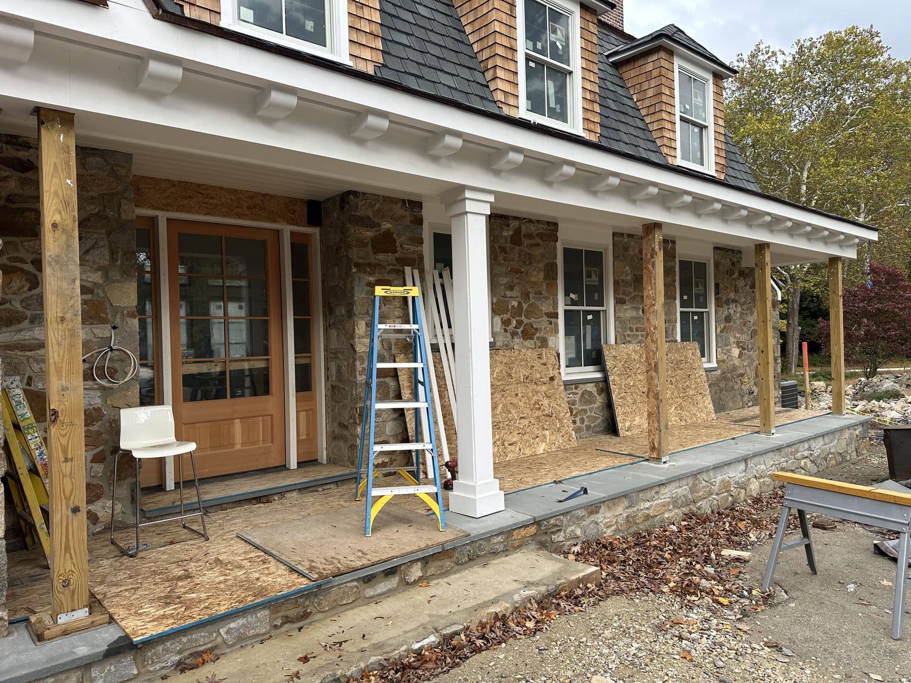 Long front porch on the stone house with new square columns going in