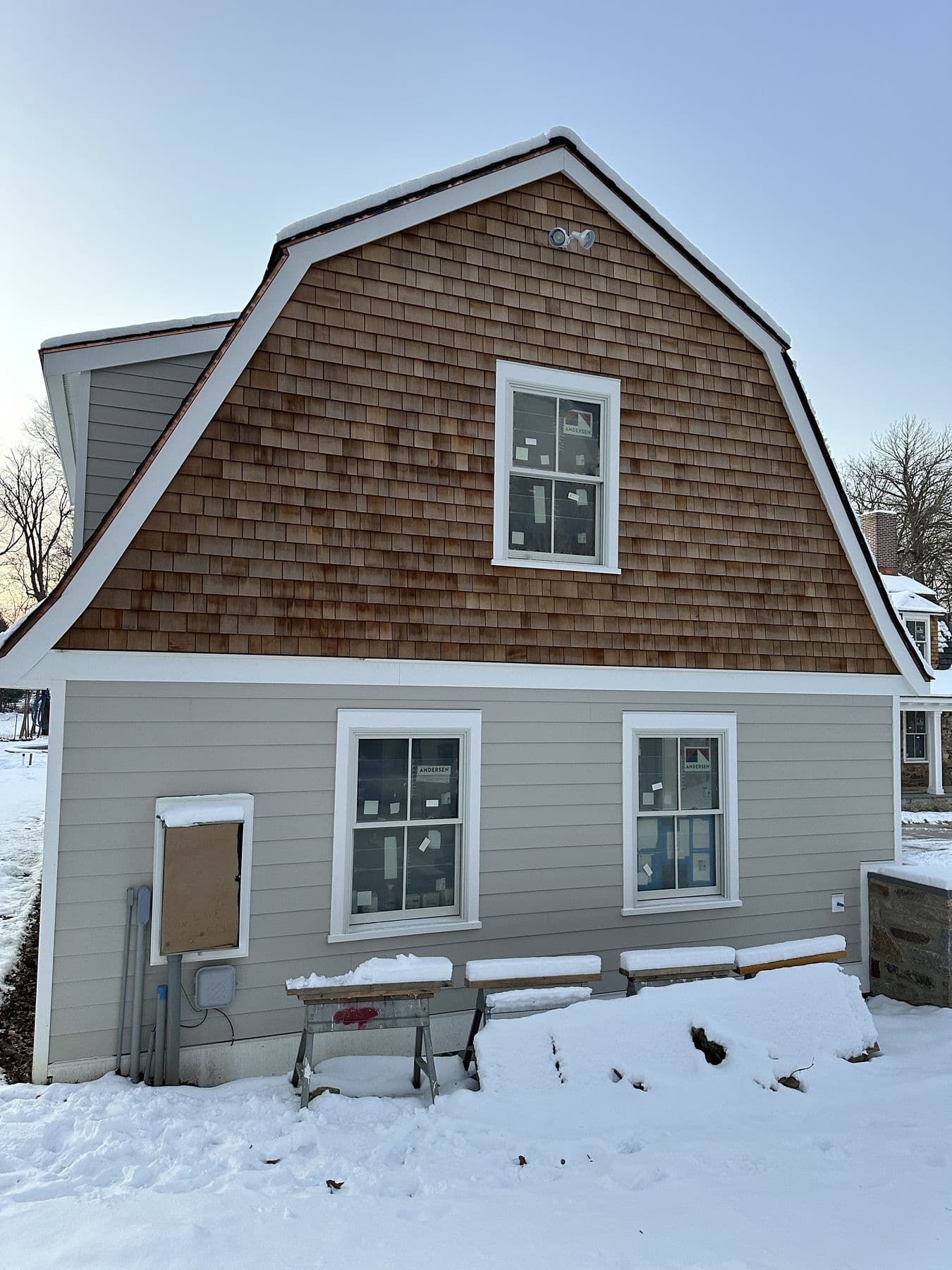 Cedar shake gambrel gable over tan lap siding on the new addition