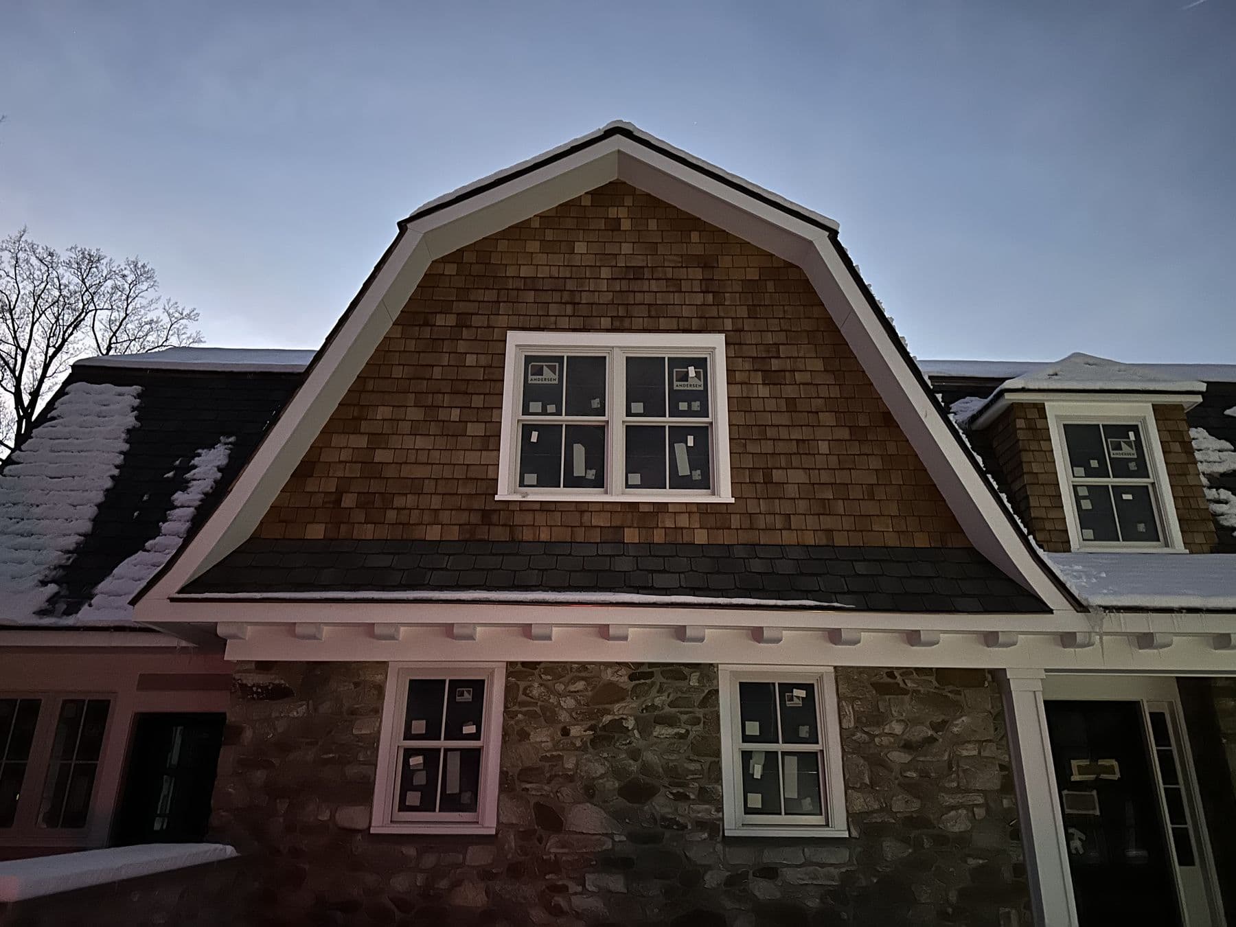 Cedar shake gambrel with three windows over the porch roof