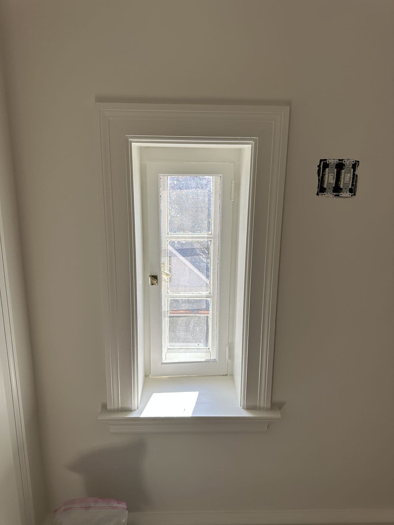 Narrow window with new casing and stool beside a door