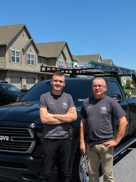 Two members of the D&E Mako crew in company shirts in front of the work truck